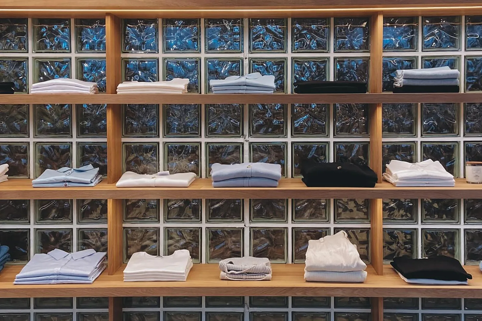 Retail display shelving with folded apparel against a glass-block feature wall