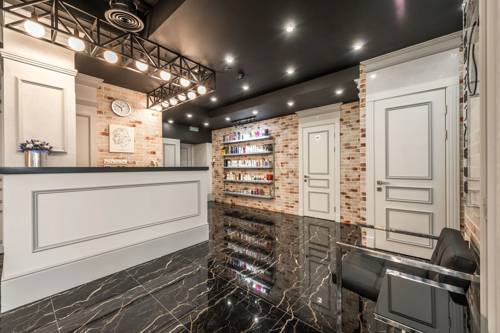 Modern salon reception desk with exposed brick, product shelving and marble flooring